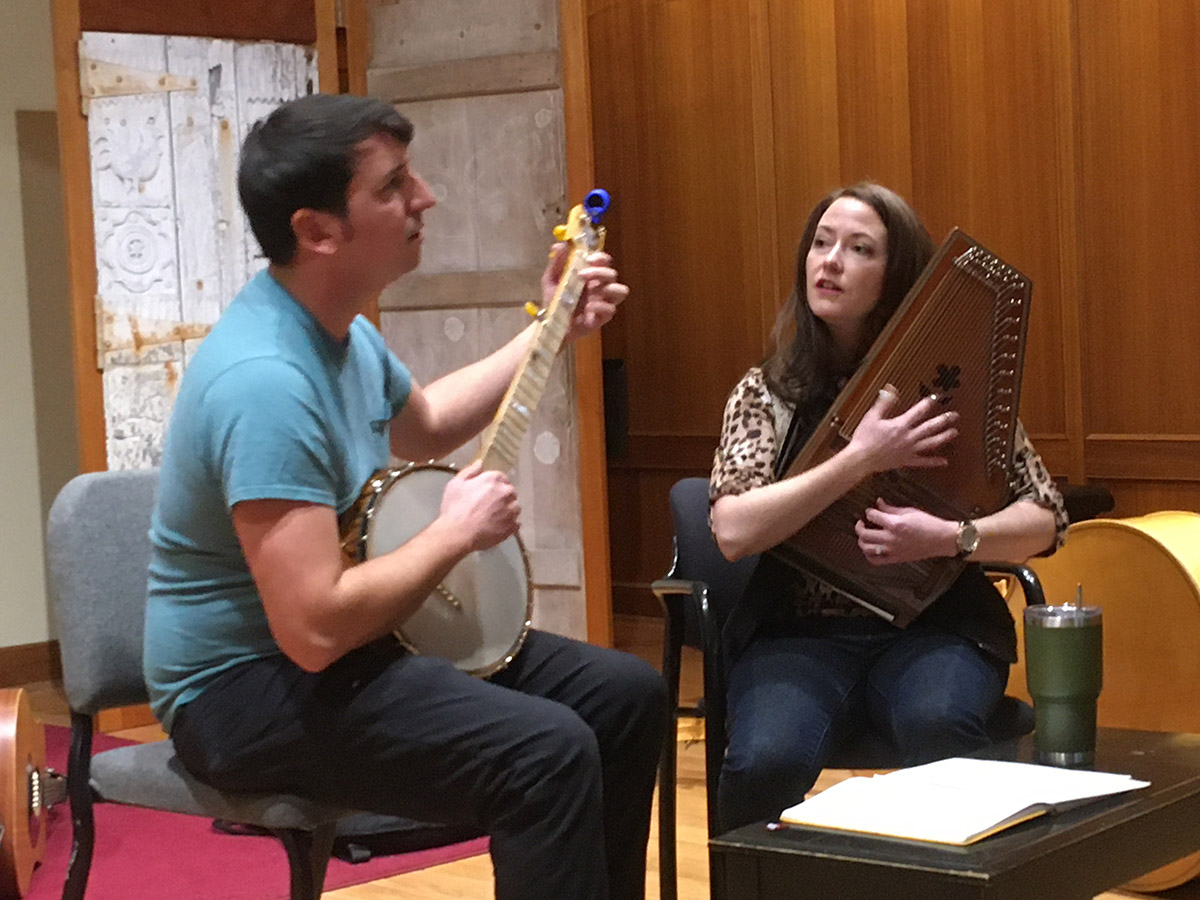 Two performers with instruments sitting and playing in the Niles Gallery.