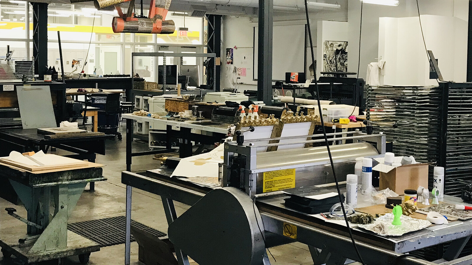 A large well lit room full of tables, huge presses, rollers, drying racks, and copious smaller pieces of equipment.