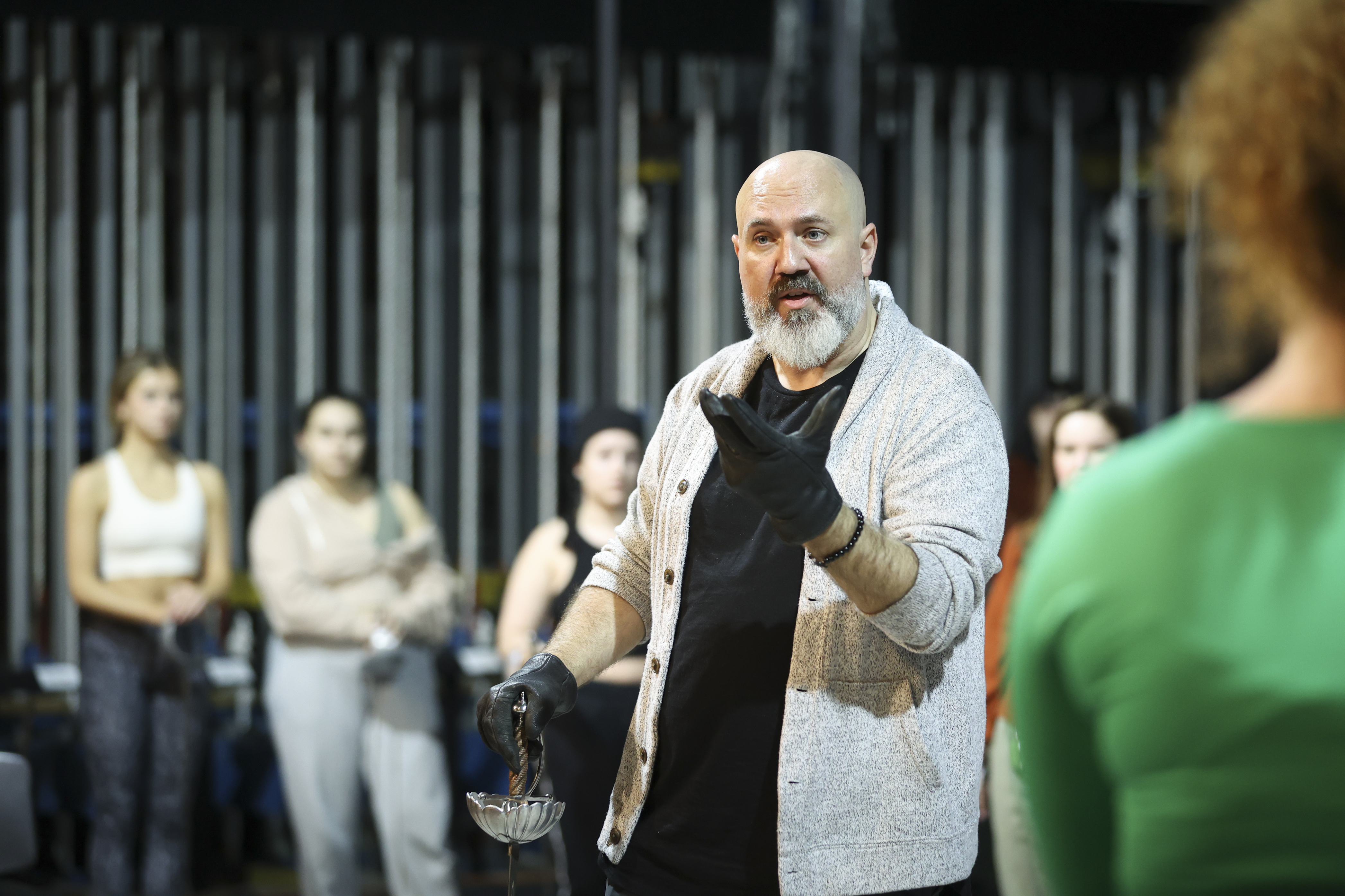 person in black gloves talking in group of students on stage
