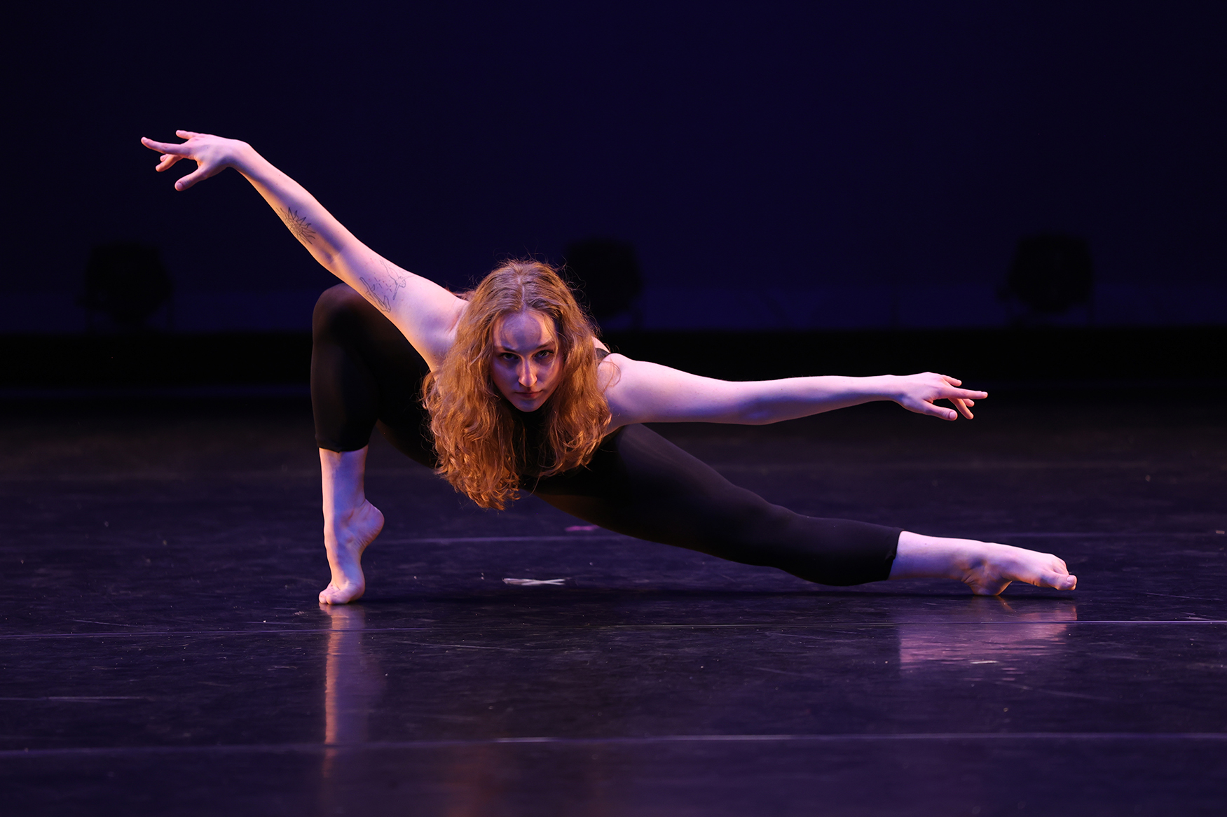 Student in deep lunge on stage looking at camera