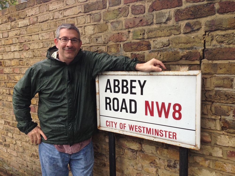Scott Frieman next to sign that says Abbey Road NW8