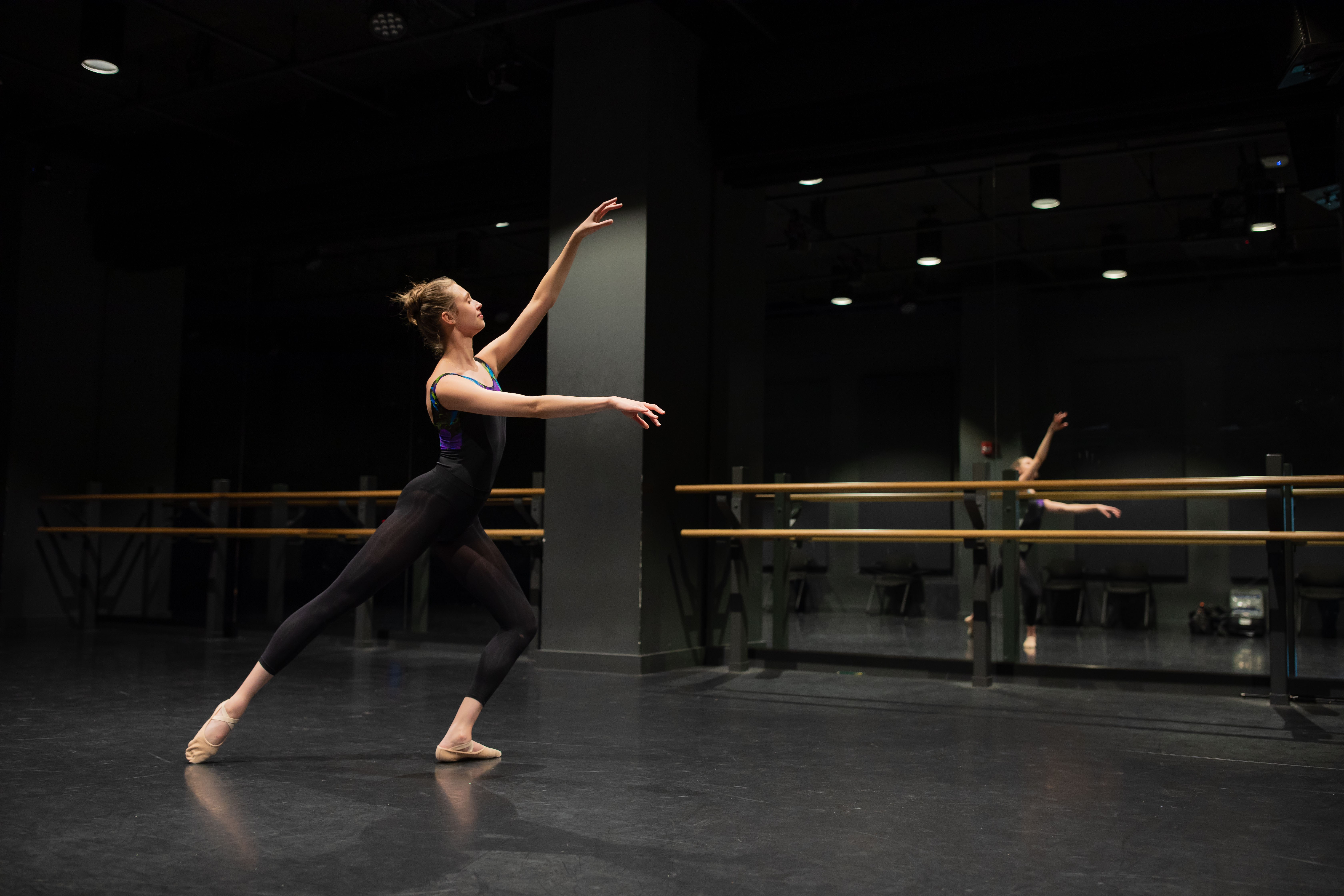 student dancing in studio with barre in background