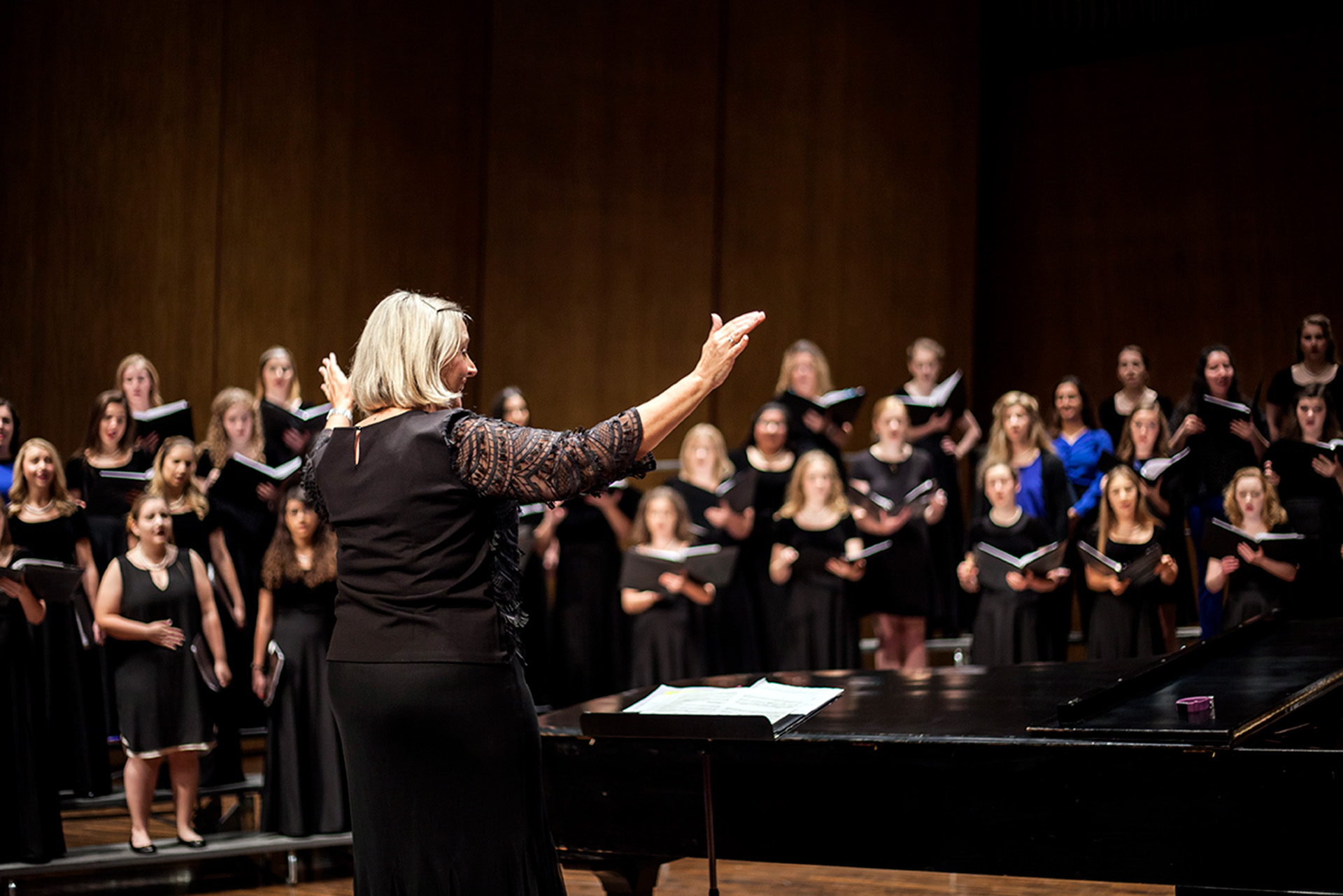 Director Dr. Lori Hetzel conducts the Treble Choir on the softly lit stage of the Singletary Center Concert Hall.