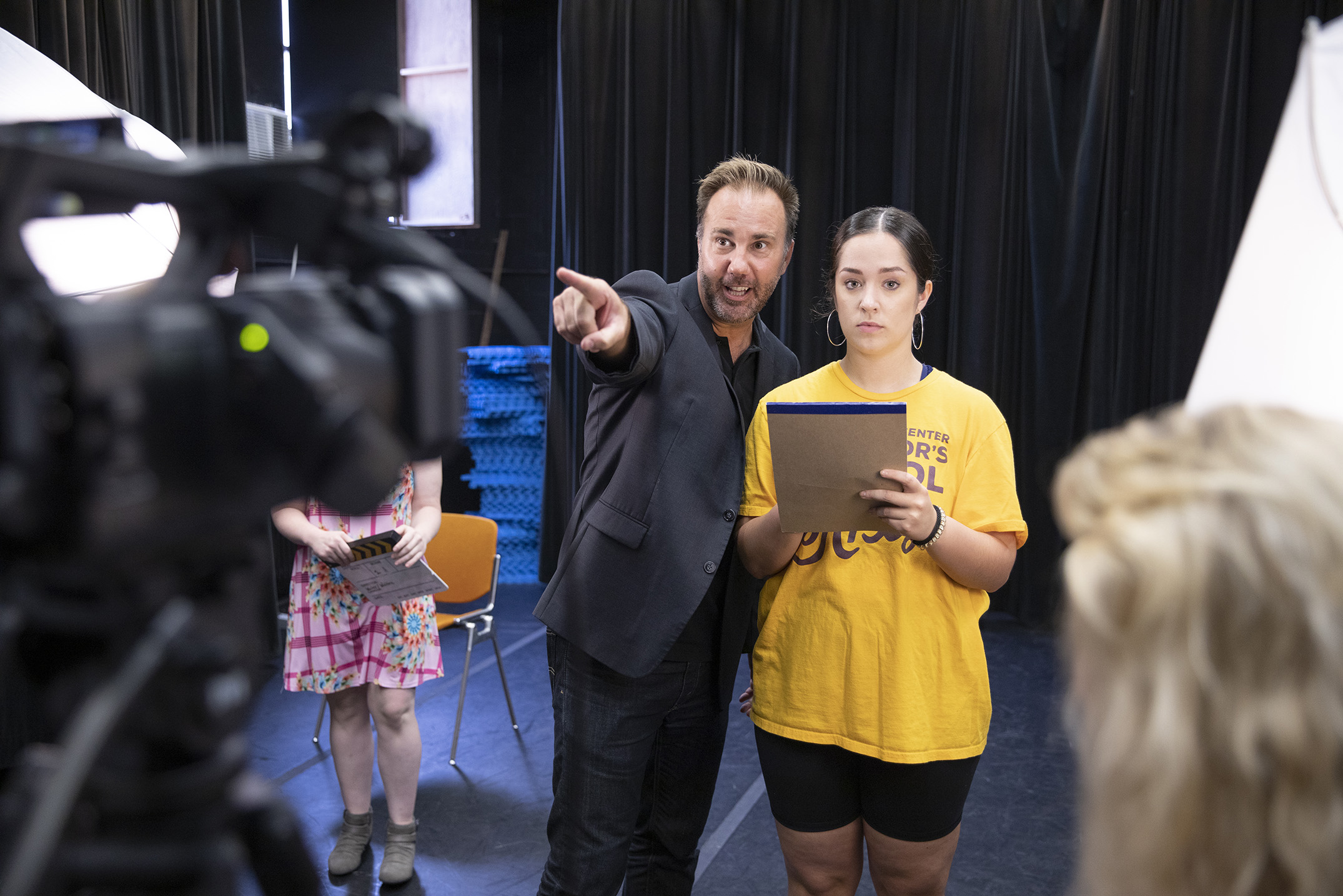 person pointing at video camera next to person in yellow shirt