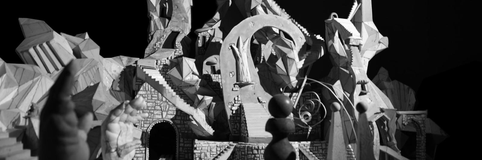 Detail view of Jay Bolotin, still image of the Carnival set. Black and white photograph of geometric, modernistic town square.