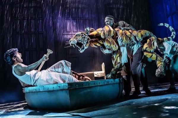 person on boat on stage with puppet tiger
