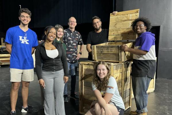 Department of Theatre and Dance Production Manager and Technical Director, Zack Stribling, joins students around a set piece onstage at the Guignol Theatre.