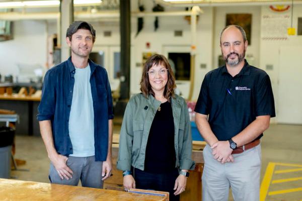 three people looking at the camera in a wood shop