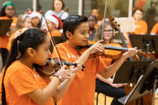 students playing violin in orange shirts