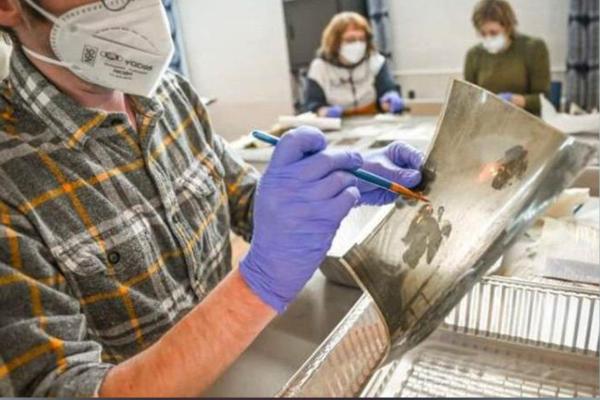 A volunteer at Hindman Settlement School helps restore a photograph following the massive Eastern Kentucky flood in July 2022. Flood waters irreparably damaged documents, photos and various works of art. Photo by Will Anderson.