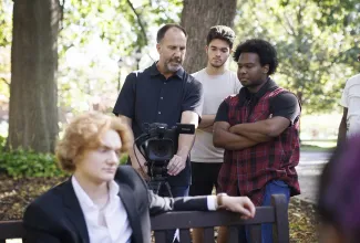 four people outside looking into video camera screen