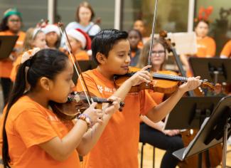 students playing violin in orange shirts