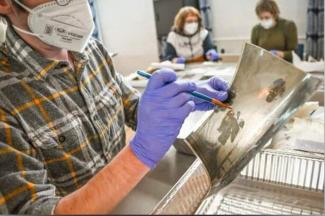 A volunteer at Hindman Settlement School helps restore a photograph following the massive Eastern Kentucky flood in July 2022. Flood waters irreparably damaged documents, photos and various works of art. Photo by Will Anderson.