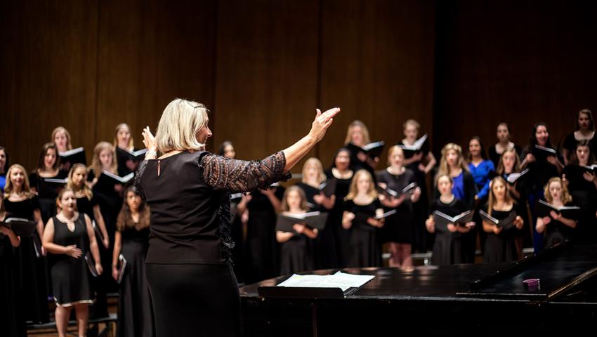 Director Dr. Lori Hetzel conducts the Treble Choir on the softly lit stage of the Singletary Center Concert Hall.