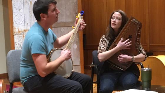 Two performers with instruments sitting and playing in the Niles Gallery.