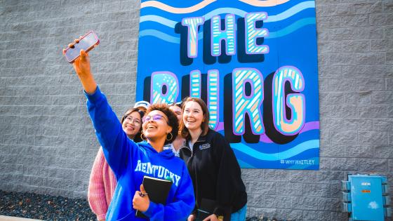 people taking selfie in front of sign