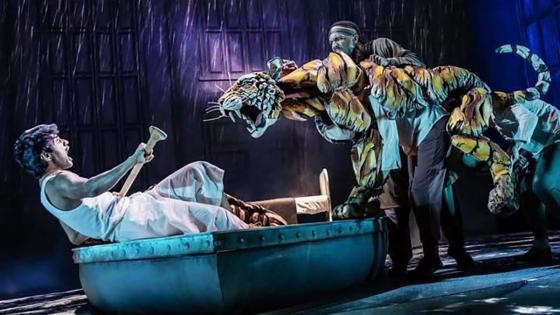 person on boat on stage with puppet tiger