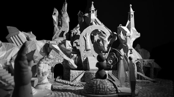 Detail view of Jay Bolotin, still image of the Carnival set. Black and white photograph of geometric, modernistic town square.