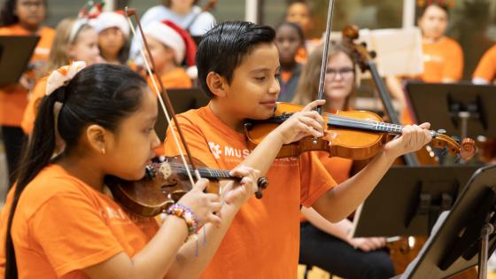 students playing violin in orange shirts