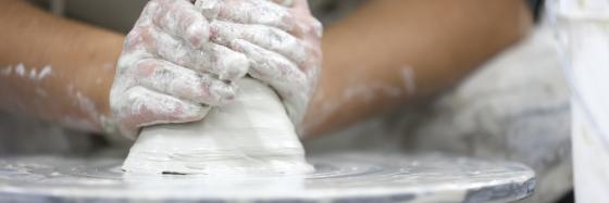 student hands close up at potter's wheel