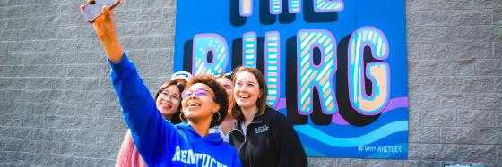 people taking selfie in front of sign