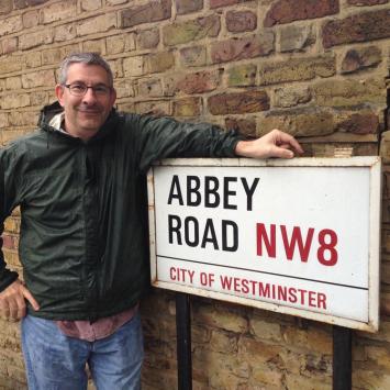 Scott Frieman next to sign that says Abbey Road NW8