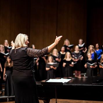 Director Dr. Lori Hetzel conducts the Treble Choir on the softly lit stage of the Singletary Center Concert Hall.