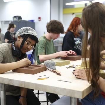 students sitting at table working on etching